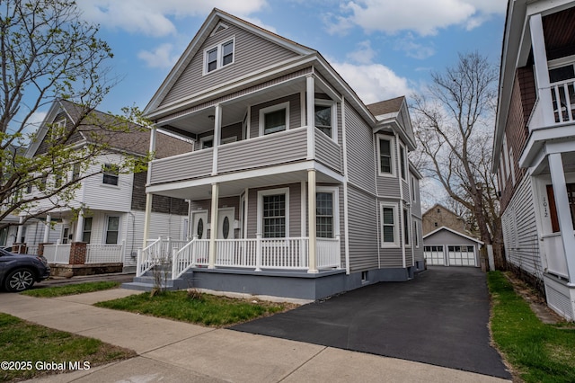 view of front of home featuring a balcony, a porch, an outbuilding, a garage, and roof with shingles