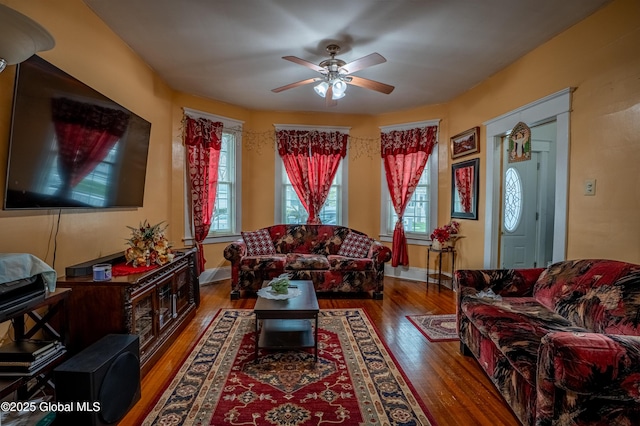 living room featuring wood finished floors, a ceiling fan, and baseboards
