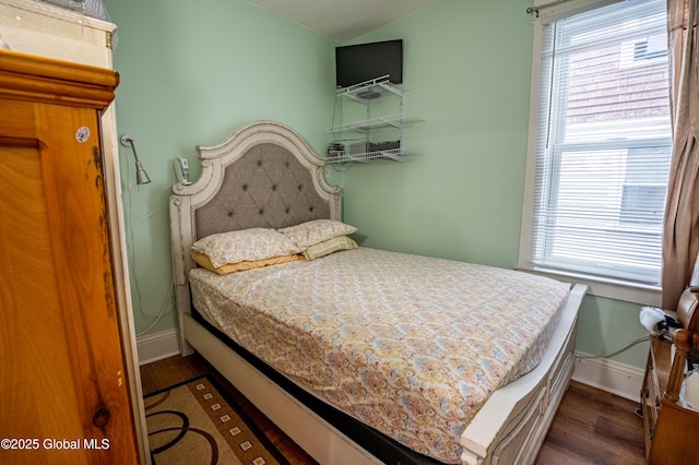 bedroom featuring baseboards, wood finished floors, and vaulted ceiling