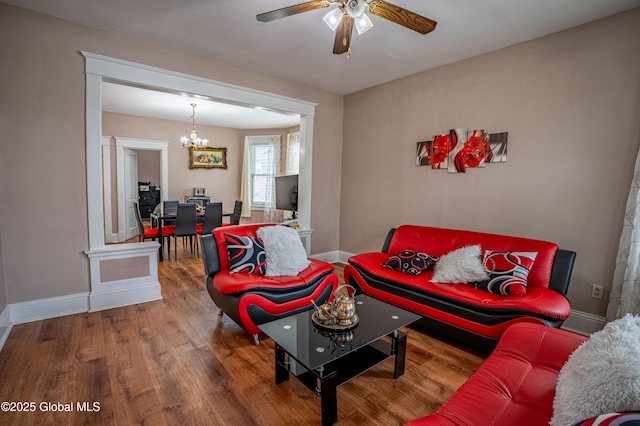 living area with a chandelier, wood finished floors, ceiling fan, and baseboards