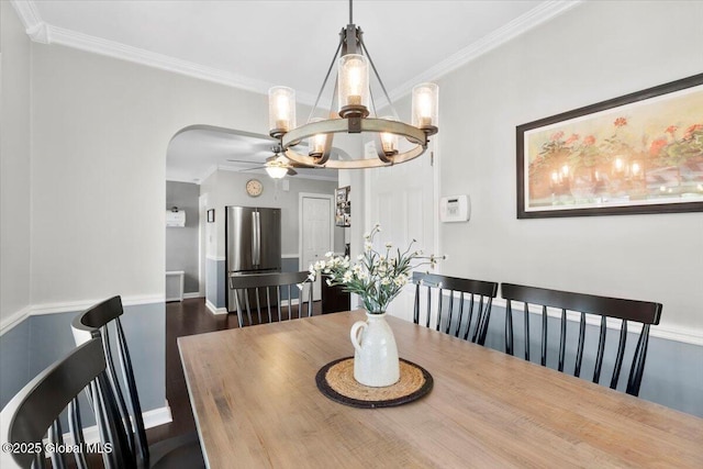 dining area featuring ornamental molding, arched walkways, ceiling fan, a chandelier, and dark wood-style flooring