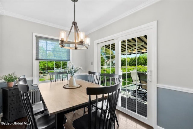 dining space with a chandelier, healthy amount of natural light, ornamental molding, and wood finished floors
