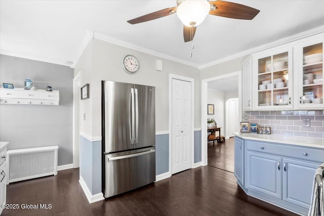 kitchen with freestanding refrigerator, light countertops, ornamental molding, a ceiling fan, and glass insert cabinets