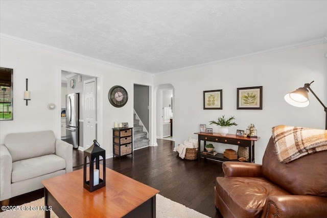living area featuring wood finished floors, stairs, arched walkways, and ornamental molding