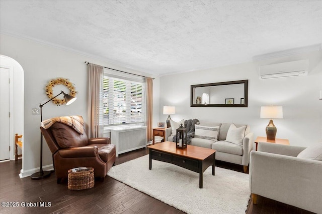 living area with radiator, a wall mounted AC, dark wood-style floors, a textured ceiling, and ornamental molding