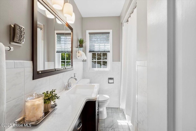 bathroom with tile walls, toilet, vanity, wainscoting, and a shower with curtain