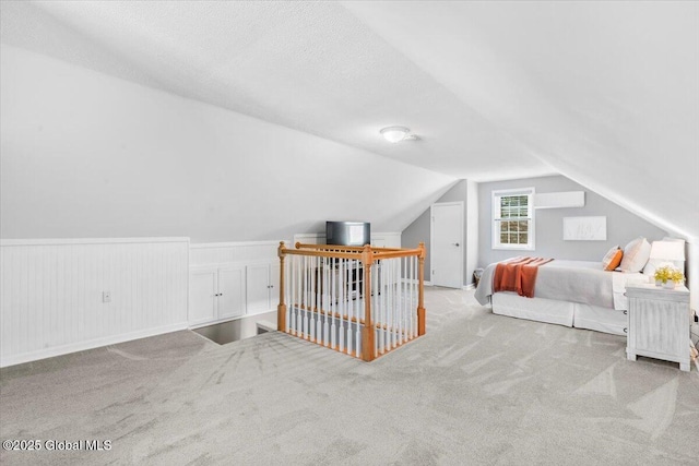 bedroom with carpet floors, lofted ceiling, and wainscoting