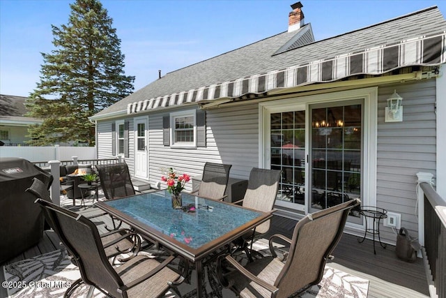 deck with outdoor dining space, fence, and area for grilling
