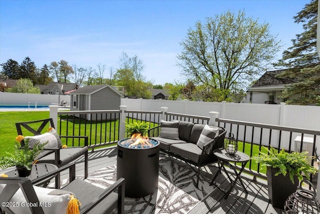 wooden deck featuring an outdoor fire pit, a storage shed, and an outdoor structure