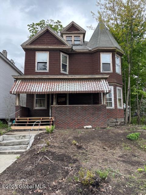 view of front of home with a porch and brick siding