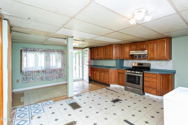 127 John St, Hudson Falls, NY 12839 - kitchen featuring gas range, a drop ceiling, brown cabinets, under cabinet range hood, and baseboards