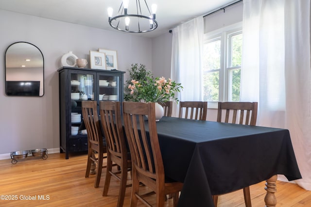 dining room featuring a chandelier, light wood-style flooring, and baseboards