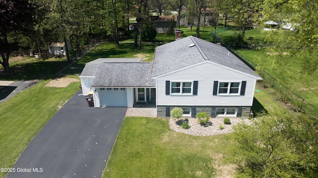 view of front of house featuring asphalt driveway, a shingled roof, a garage, and a front yard
