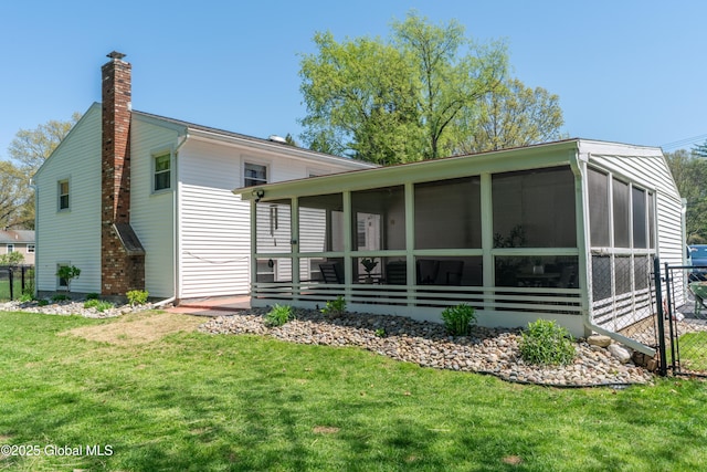 back of property featuring a yard, a chimney, and a sunroom