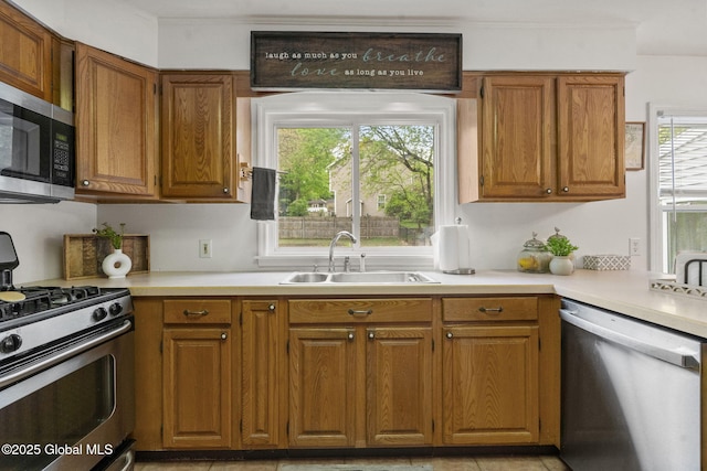 15 Oak Tree Ln, Colonie, NY 12309 - kitchen with stainless steel appliances, a sink, brown cabinets, light countertops, and crown molding
