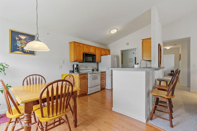 kitchen with white appliances, lofted ceiling, a kitchen bar, a peninsula, and a sink