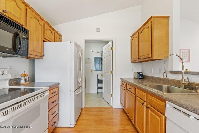 kitchen with white appliances, a sink, vaulted ceiling, light wood-style flooring, and brown cabinetry