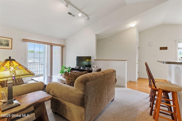 living area featuring lofted ceiling, track lighting, carpet floors, and baseboards