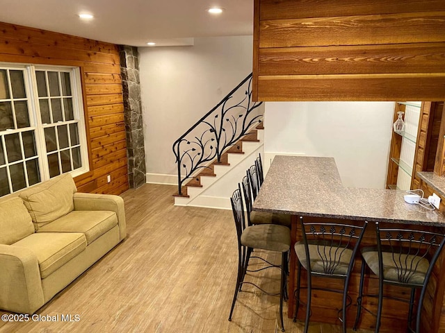 living room with wood finished floors, wood walls, stairs, baseboards, and recessed lighting