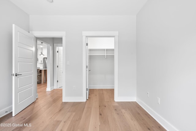 116 W Ave Unit 309, Saratoga Springs, NY 12866 - unfurnished bedroom featuring baseboards, light wood finished floors, a spacious closet, and a closet