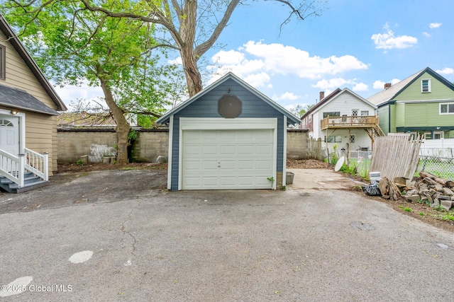 detached garage featuring fence and driveway