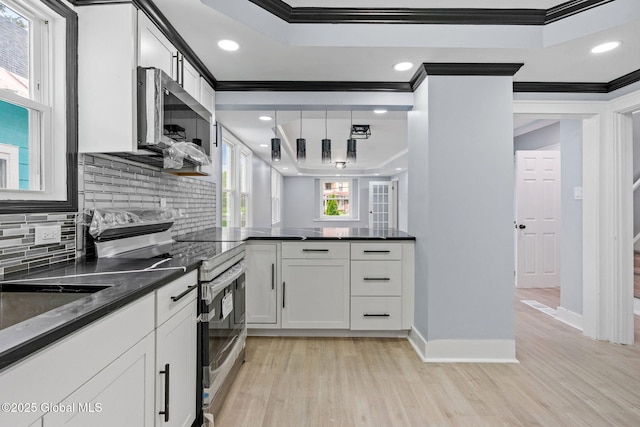 kitchen with ornamental molding, stainless steel appliances, light wood-type flooring, a raised ceiling, and tasteful backsplash