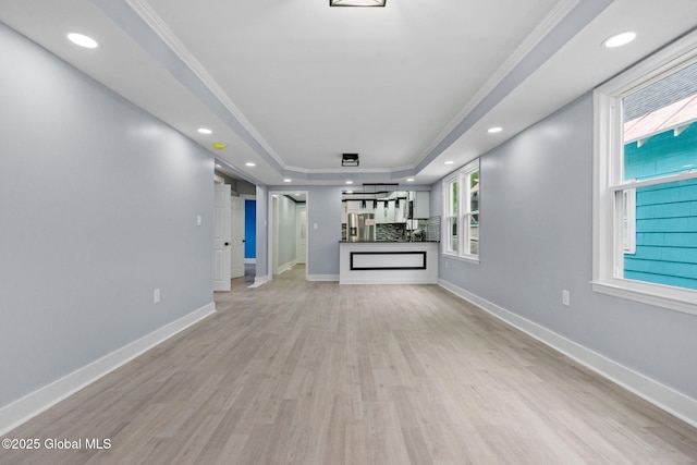 unfurnished living room featuring a tray ceiling, light wood-type flooring, plenty of natural light, baseboards, and recessed lighting