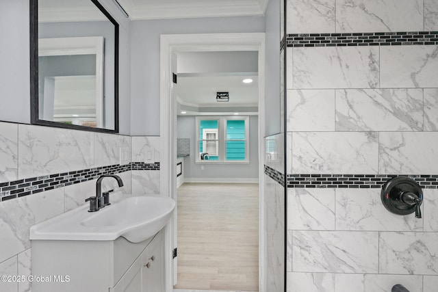 bathroom featuring ornamental molding, vanity, tiled shower, and wood finished floors