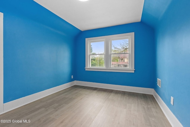 additional living space with wood finished floors, lofted ceiling, and baseboards