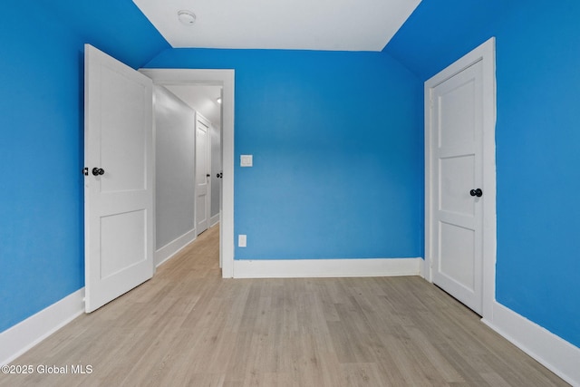 spare room with lofted ceiling, wood finished floors, baseboards, and a smoke detector