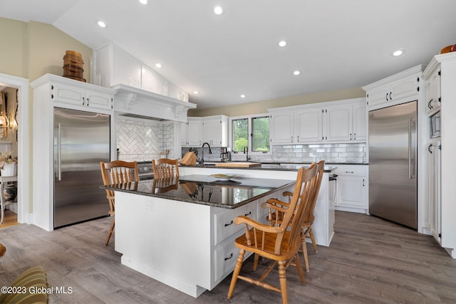 6510 State Route 10, Seward, NY 13459 - kitchen with built in refrigerator, vaulted ceiling, white cabinets, a breakfast bar area, and recessed lighting