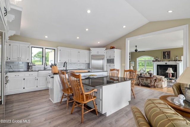 6510 State Route 10, Seward, NY 13459 - kitchen featuring built in appliances, a center island with sink, a breakfast bar area, white cabinetry, and lofted ceiling