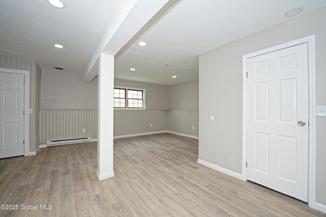 below grade area with a baseboard heating unit, light wood-style floors, a wainscoted wall, recessed lighting, and baseboards