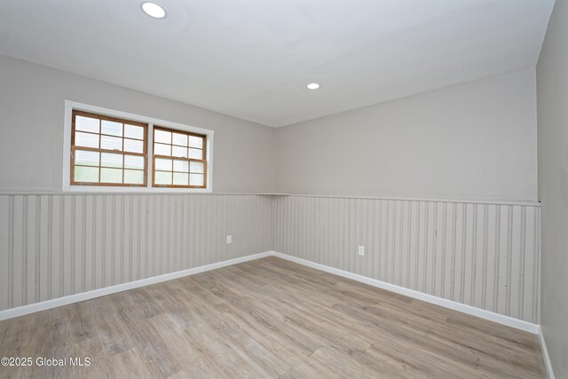 spare room featuring light wood finished floors, wainscoting, recessed lighting, and baseboards