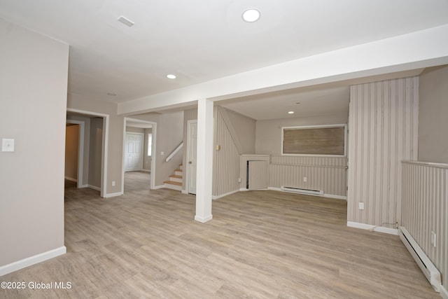 finished basement with baseboard heating, baseboards, stairs, light wood finished floors, and recessed lighting