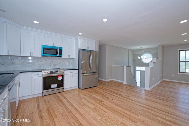 kitchen featuring appliances with stainless steel finishes, tasteful backsplash, light wood finished floors, dark countertops, and recessed lighting