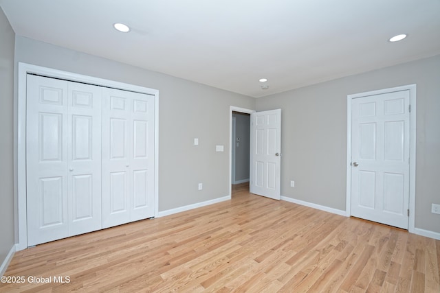 unfurnished bedroom with light wood finished floors, baseboards, recessed lighting, and a closet