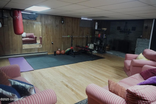 exercise room with a drop ceiling, wood finished floors, and wooden walls