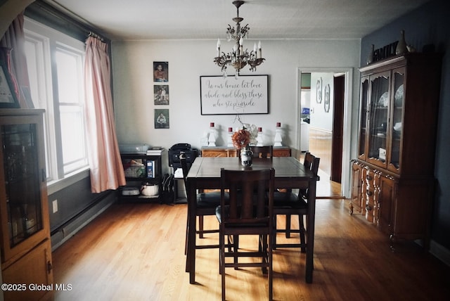dining room featuring a chandelier, light wood-style floors, and a baseboard heating unit
