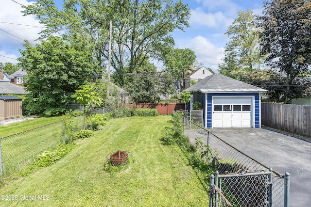1250 Dean St, Niskayuna, NY 12309 - view of yard featuring asphalt driveway, an outdoor structure, a detached garage, and a fire pit