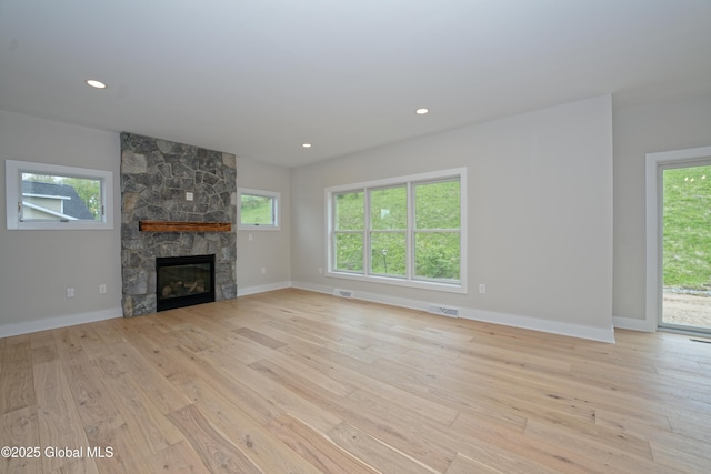 unfurnished living room featuring light wood finished floors, a fireplace, baseboards, and recessed lighting