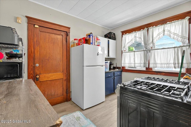 kitchen with freestanding refrigerator, light wood-style floors, crown molding, black range with gas stovetop, and brown cabinets