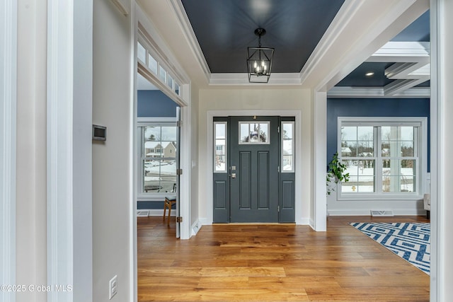 foyer featuring a chandelier, light wood-type flooring, plenty of natural light, baseboards, and crown molding