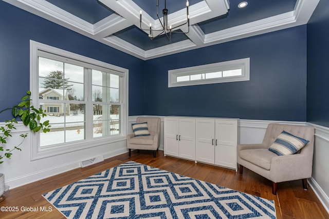 sitting room featuring a chandelier, coffered ceiling, dark wood finished floors, beam ceiling, and a wainscoted wall