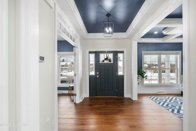 entrance foyer featuring hardwood / wood-style floors, healthy amount of natural light, a chandelier, baseboards, and crown molding