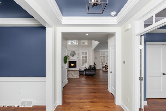 corridor featuring wood finished floors, a chandelier, baseboards, and ornamental molding