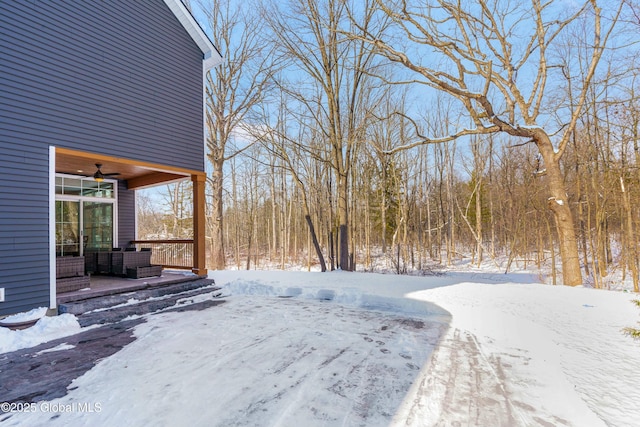 snowy yard with a ceiling fan and an outdoor living space