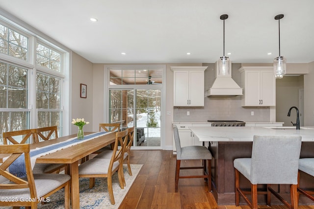 kitchen with custom range hood, a sink, decorative backsplash, dark wood-style floors, and white cabinetry