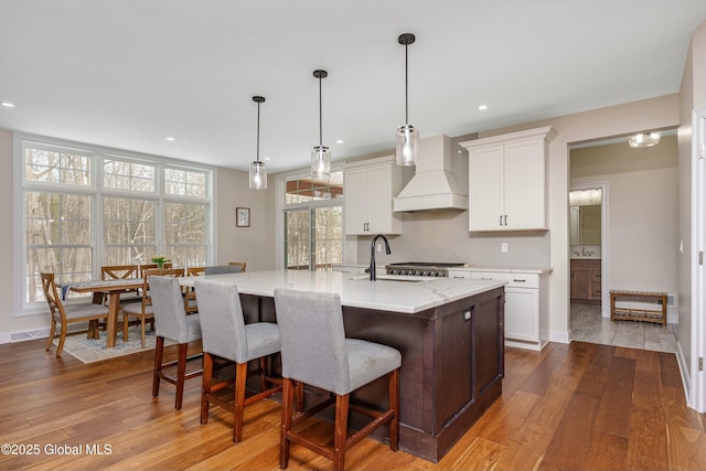 kitchen featuring custom range hood, a sink, tasteful backsplash, dark wood-style floors, and recessed lighting