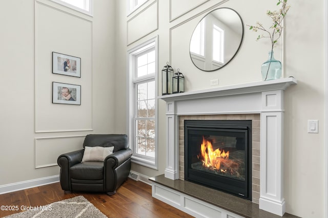 living area with dark wood-type flooring, baseboards, a tile fireplace, and healthy amount of natural light